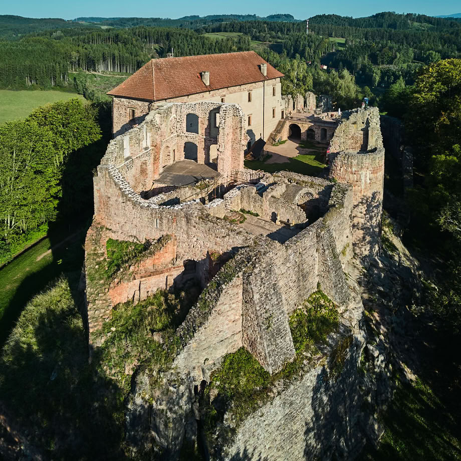 A serene A-frame cabin surrounded by lush greenery under a clear blue sky.